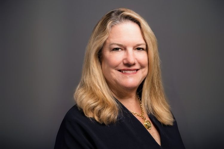 a headshot of a woman in front of a grey background