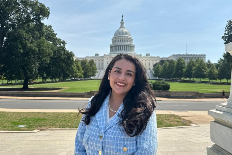 A woman poses for a photo in front of the U.S. Capitol Building 