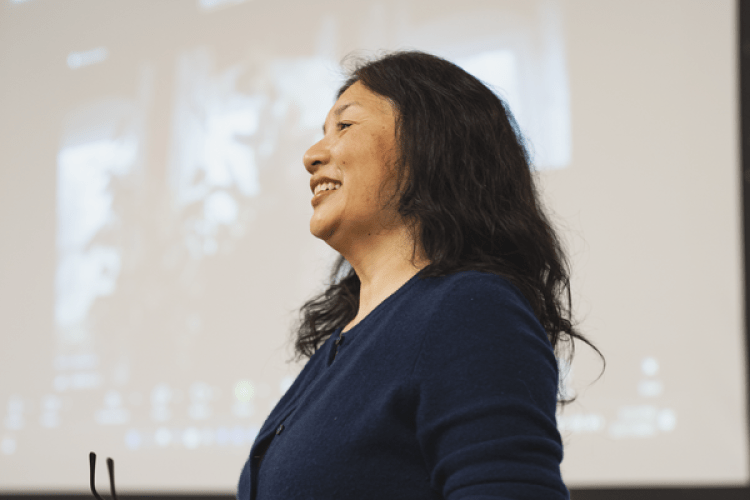 A woman stands in front of a whiteboard 