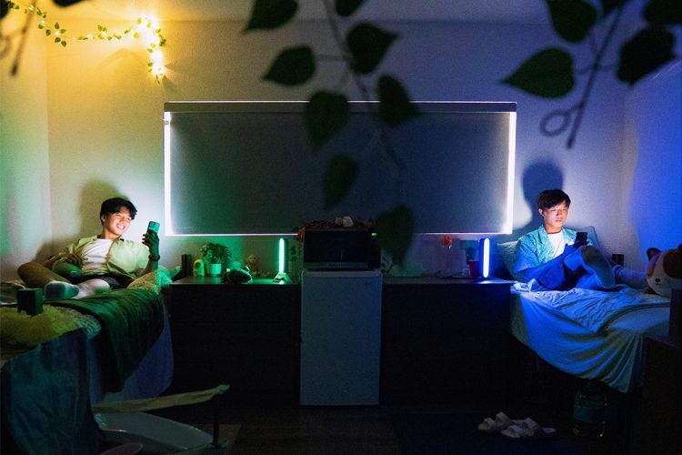 students sit in bed looking at their phones