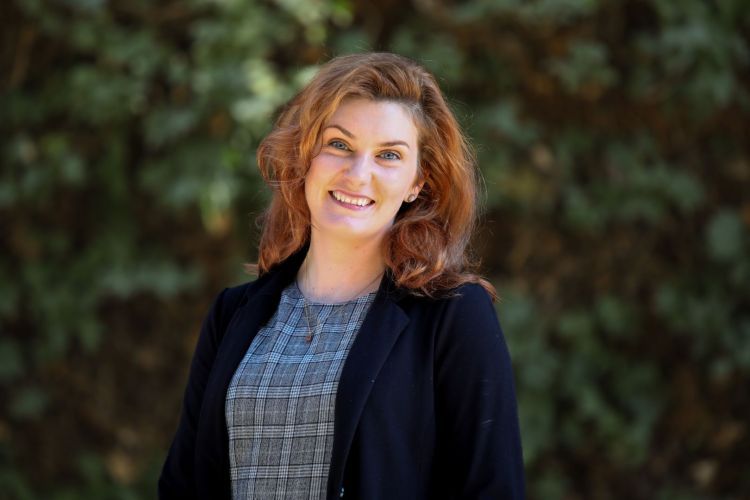 Woman in business attire smiling in an outdoor setting