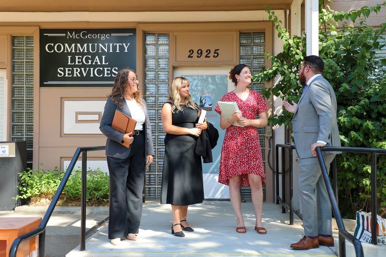 Four people smile and pose in front of the clinics building