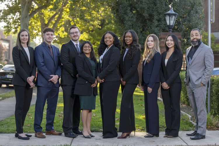 A group of nine people pose for a photo outdoors
