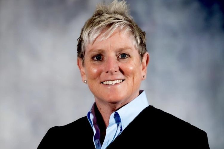 A portrait of a woman in a black jacket against a neutral backdrop.