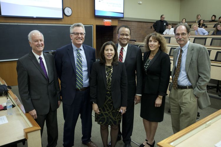 A group of professionally dressed individuals stand for a group photo. 