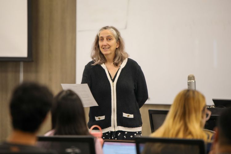 A professor teaching a class with students in the background. 