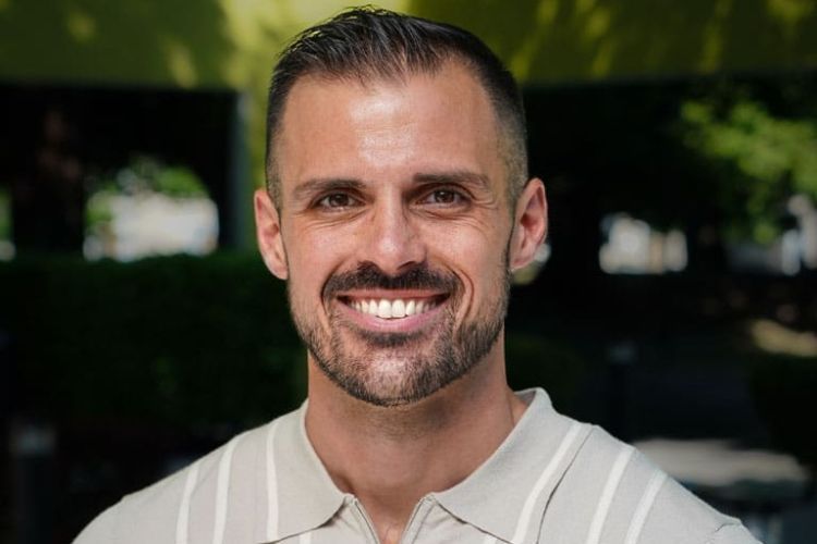 A man with short black hair wearing a stripped collared shirt. 