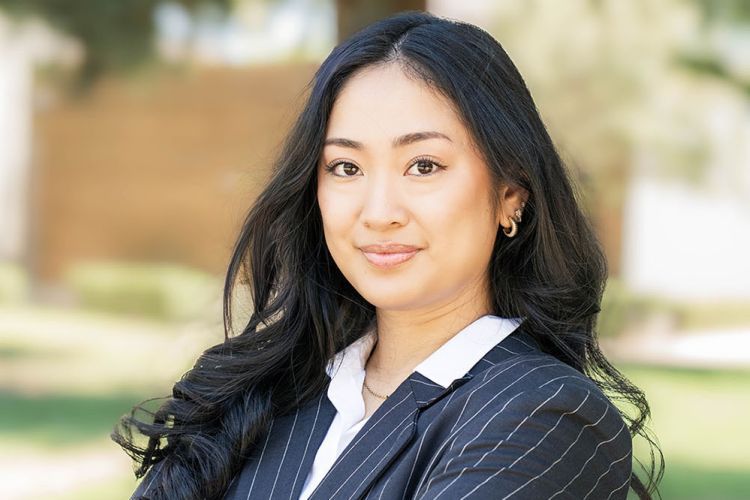 A women with long curled black hair wearing a black and white stripped jacket.