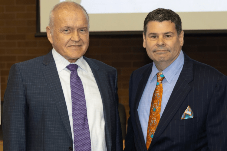 Mark Drobny and Michael T. Colatrella Jr. smile in front of a presentation