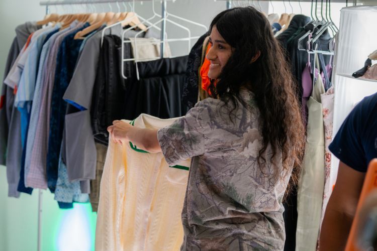 a student holds up a shirt in front of a clothing rack