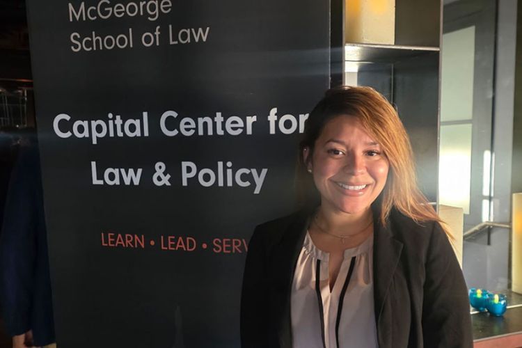 A woman stands in front of a sign that reads "Capital center for Law and Policy."