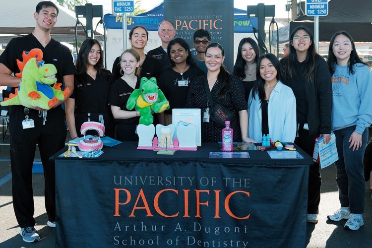 twelve people at a table outside with University of the Pacific, Arthur A. Dugoni School of Dentistry banner