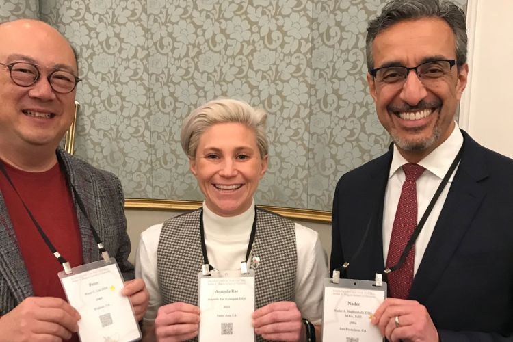 Three people standing in a room holding placards with their titles