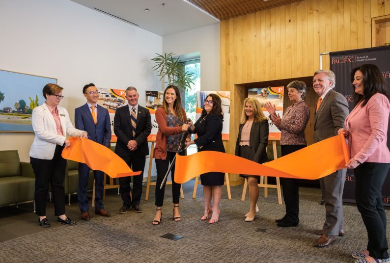 Students, faculty and university leaders hold a ribbon cutting ceremony