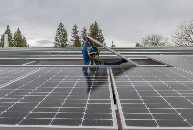 A worker installs a solar panel on Pacific's campus