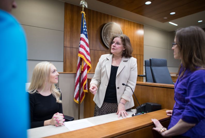 A female teacher talks to three students in a courtroom