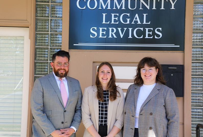 Three people pose for a photo outside of a building.