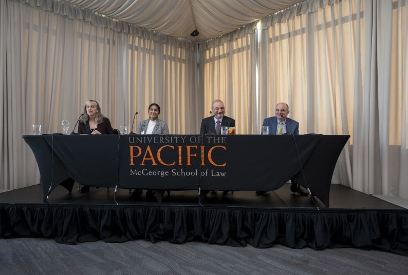 Four people behind a table speaking on a panel
