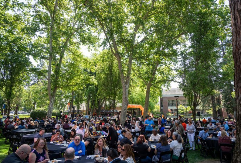 Staff and faculty sit at tables during a luncheon held outside on University of the Pacific's Stockton Campus.