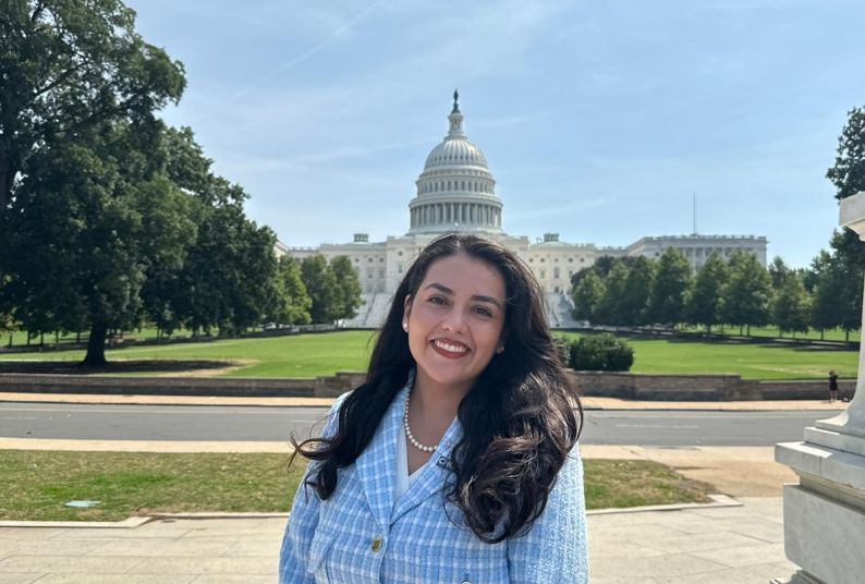 A woman poses for a photo in front of the U.S. Capitol Building 