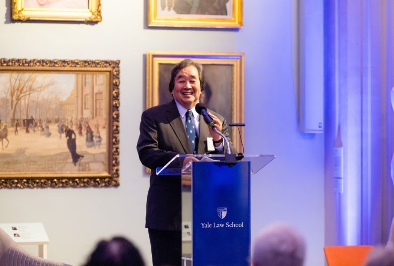 A portrait of a man speaking at a podium