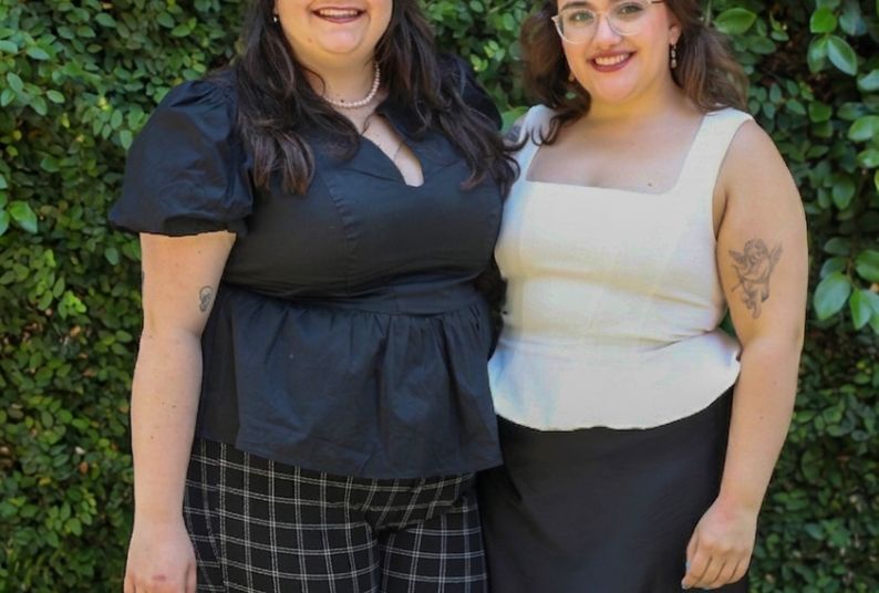 Two people stand against a green background for a professional photo. 