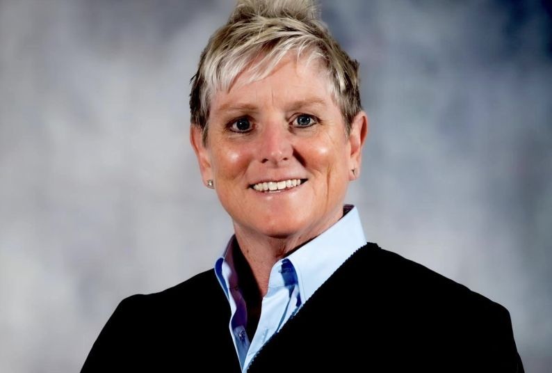 A portrait of a woman in a black jacket against a neutral backdrop.