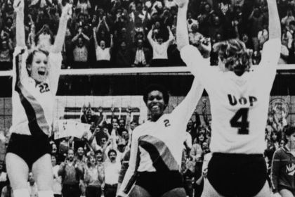 Three Pacific volleyball players celebrate their championship win. 