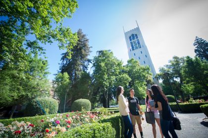 Four students stand in front of Burns Tower