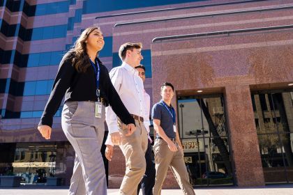 Four students walk in front of Stockton city building
