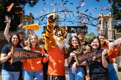 students pose for a picture with Powercat as confetti flies around them