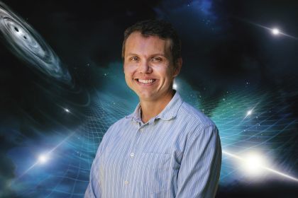 Assistant Professor of Physics Dustin (“Dusty”) Madison in front of an image of space