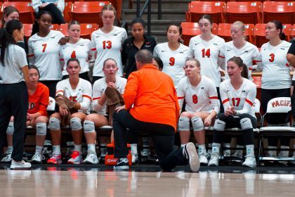 Volleyball team gathers around their coach