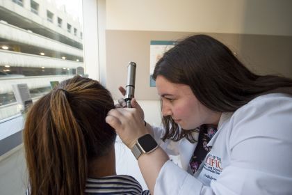 an audiology student examins a patient