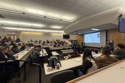 A classroom full of people listen to a presentation