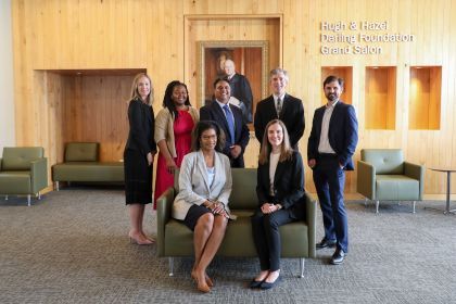 Seven professors smile for a photo, two are seated