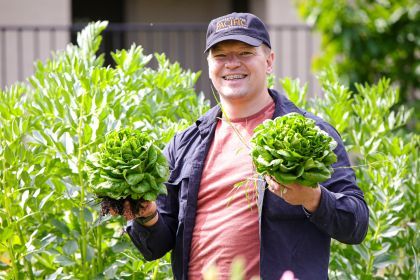 A man holds vegetables in a garden
