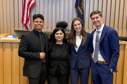 Four law students pose for a photo in a courtroom