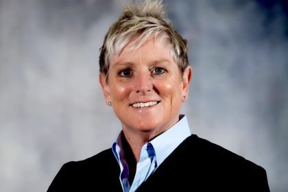 A portrait of a woman in a black jacket against a neutral backdrop.