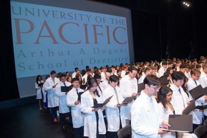 Students stand at their white coat ceremony.