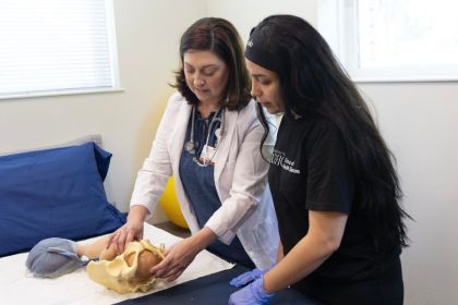 A professor showing a students a midwifery technique with a model.