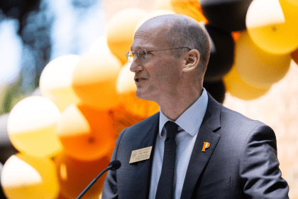 James Walsh stands in front of balloons as he gives a speech