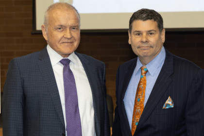 Mark Drobny and Michael T. Colatrella Jr. smile in front of a presentation