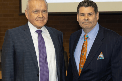 Mark Drobny and Michael T. Colatrella Jr. smile in front of a presentation