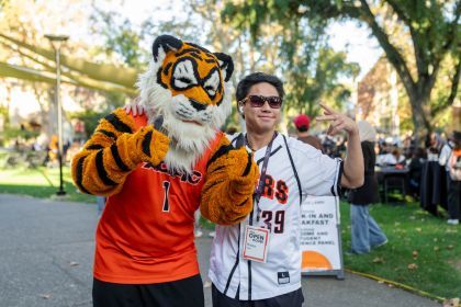 A student in a jersey smiles for a photo with Powercat.