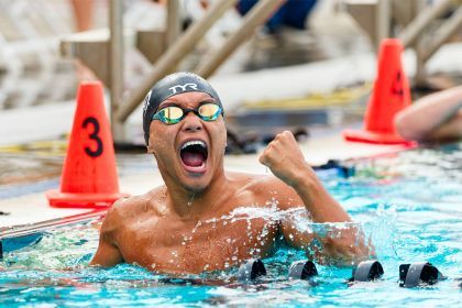 A swimmer in googles pumps his fist in victory in the pool.