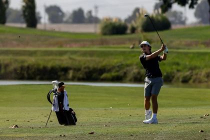 Bouchard swinging a gold club on a green course.