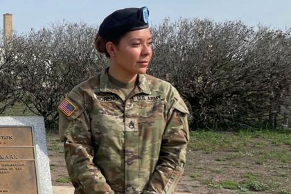 A woman in an Army uniform stand to get her photo taken.