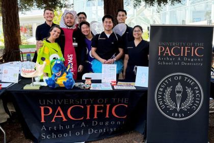 Eight people at a table outside with University of the Pacific, Arthur A. Dugoni School of Dentistry banner