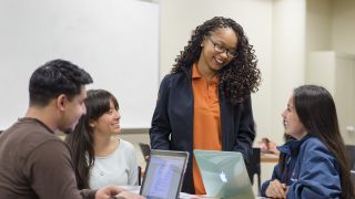 A professor with students using laptops